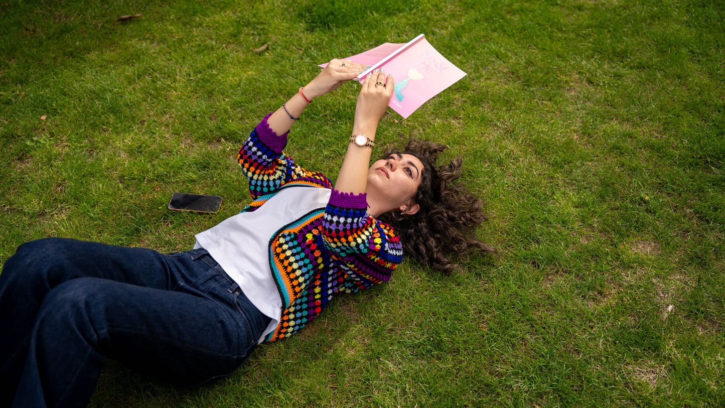 Model wearing rainbow granny square crochet cardigan, front selfie view