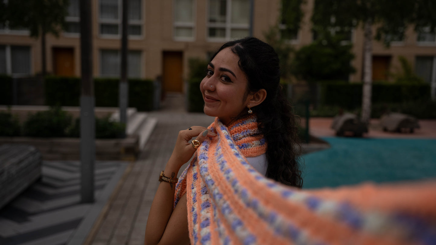 Model smiling wearing peach and lilac crochet scarf, close-up