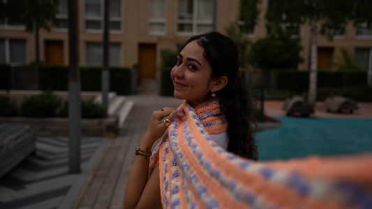 Model smiling wearing peach and lilac crochet scarf, close-up
