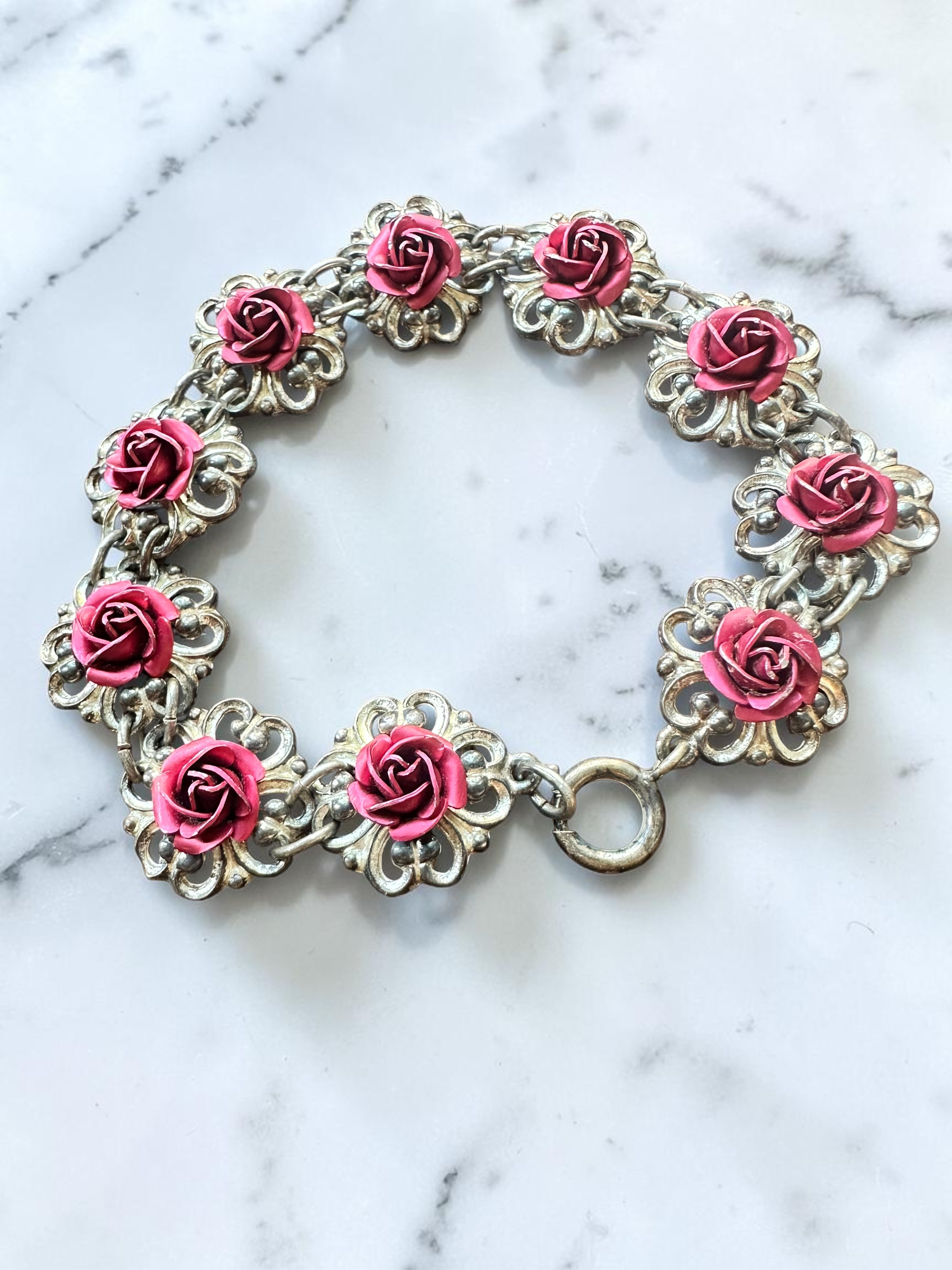 Vintage pink rose silver tone filigree link bracelet, circular view on marble