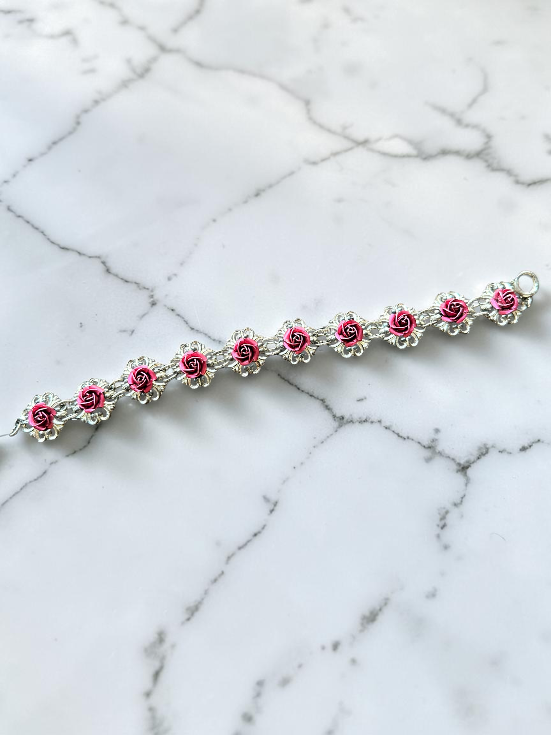 Vintage pink rose silver tone filigree link bracelet, laid flat on marble