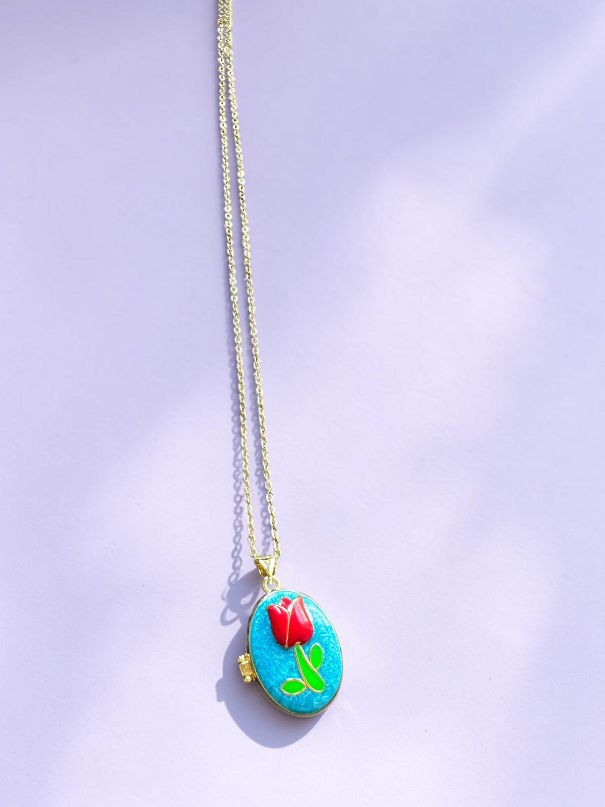 Enamel tulip locket necklace, full length view on purple background