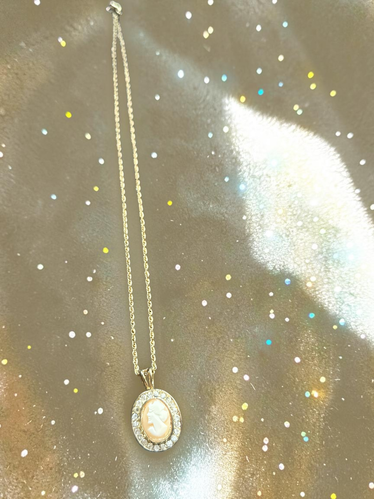 Vintage real cameo crystal halo gold tone necklace, overhead view on glitter background