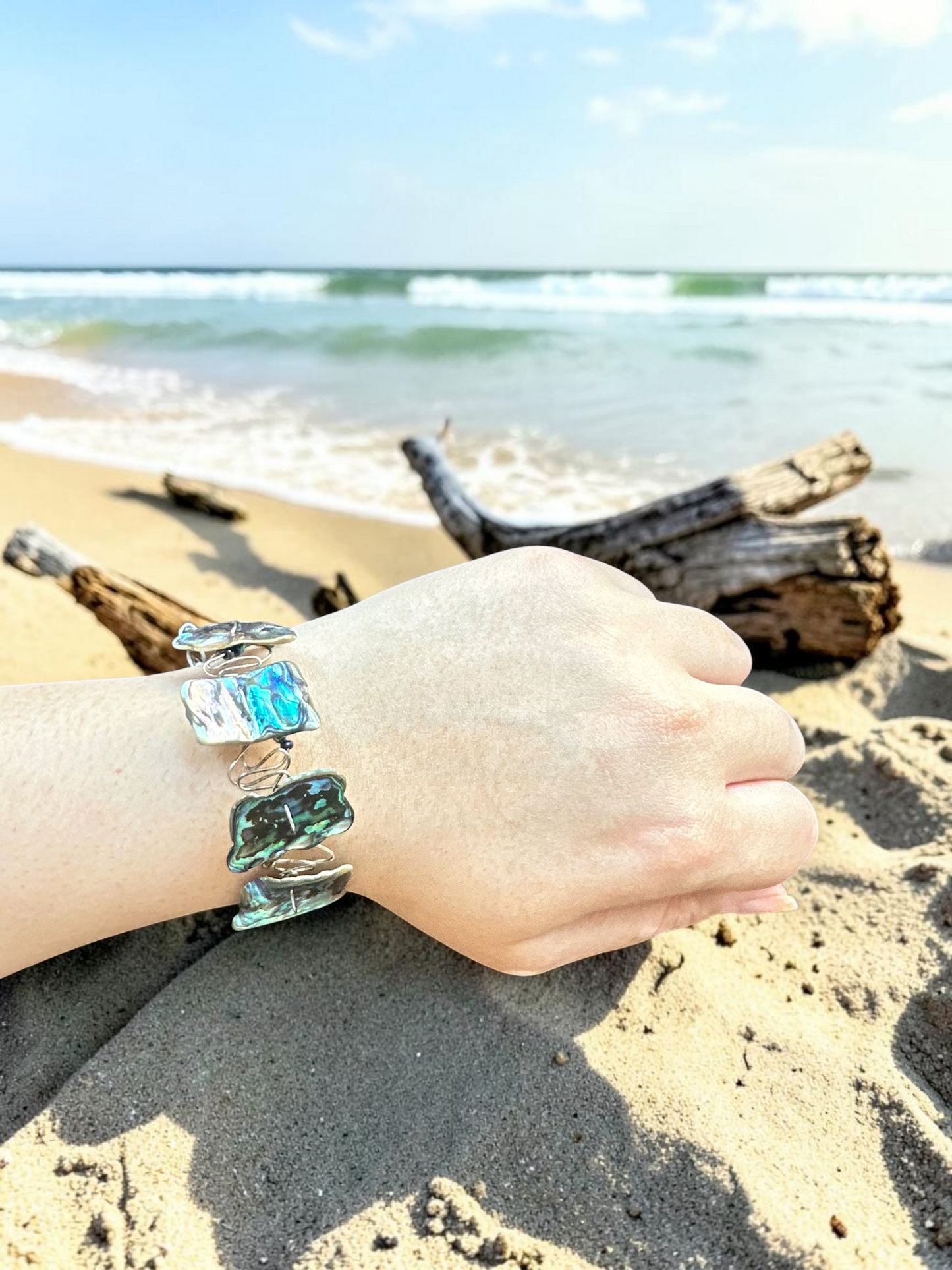 Handcrafted abalone shell wire wrapped bracelet worn on wrist at the beach