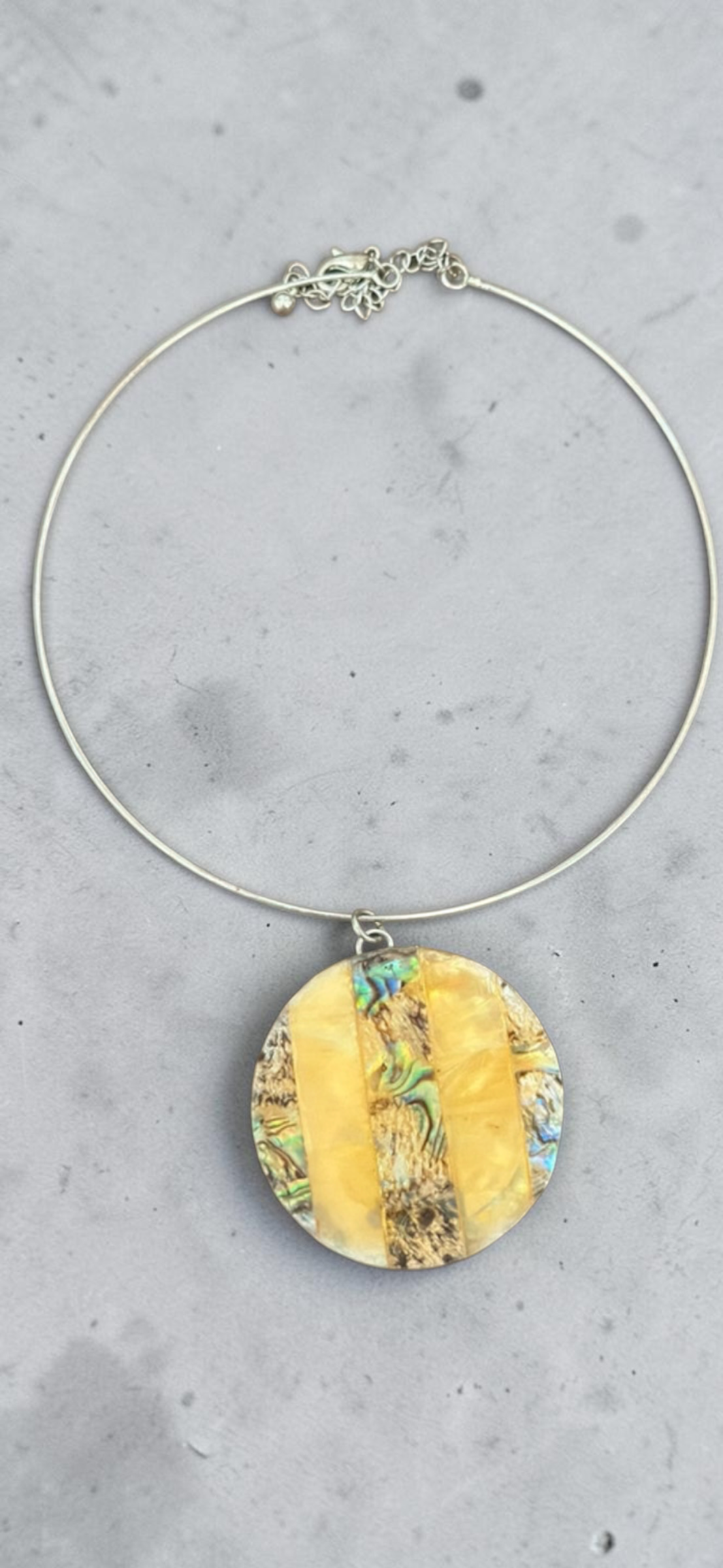 Yellow abalone shell disc choker necklace, pendant detail on concrete