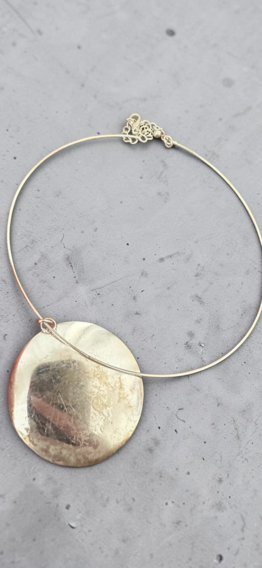 Yellow abalone shell disc choker necklace, reverse gold shell side on concrete
