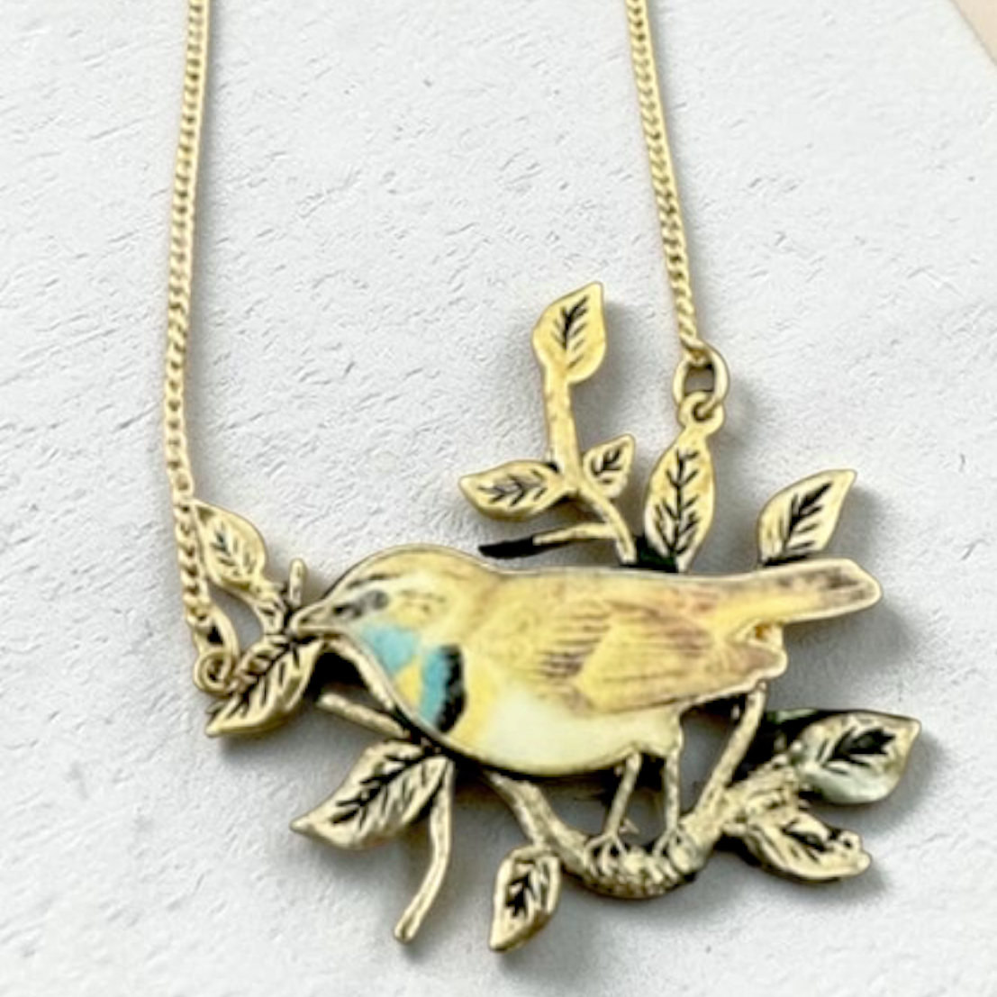 Enamel bird on branch gold tone necklace, full length on white background