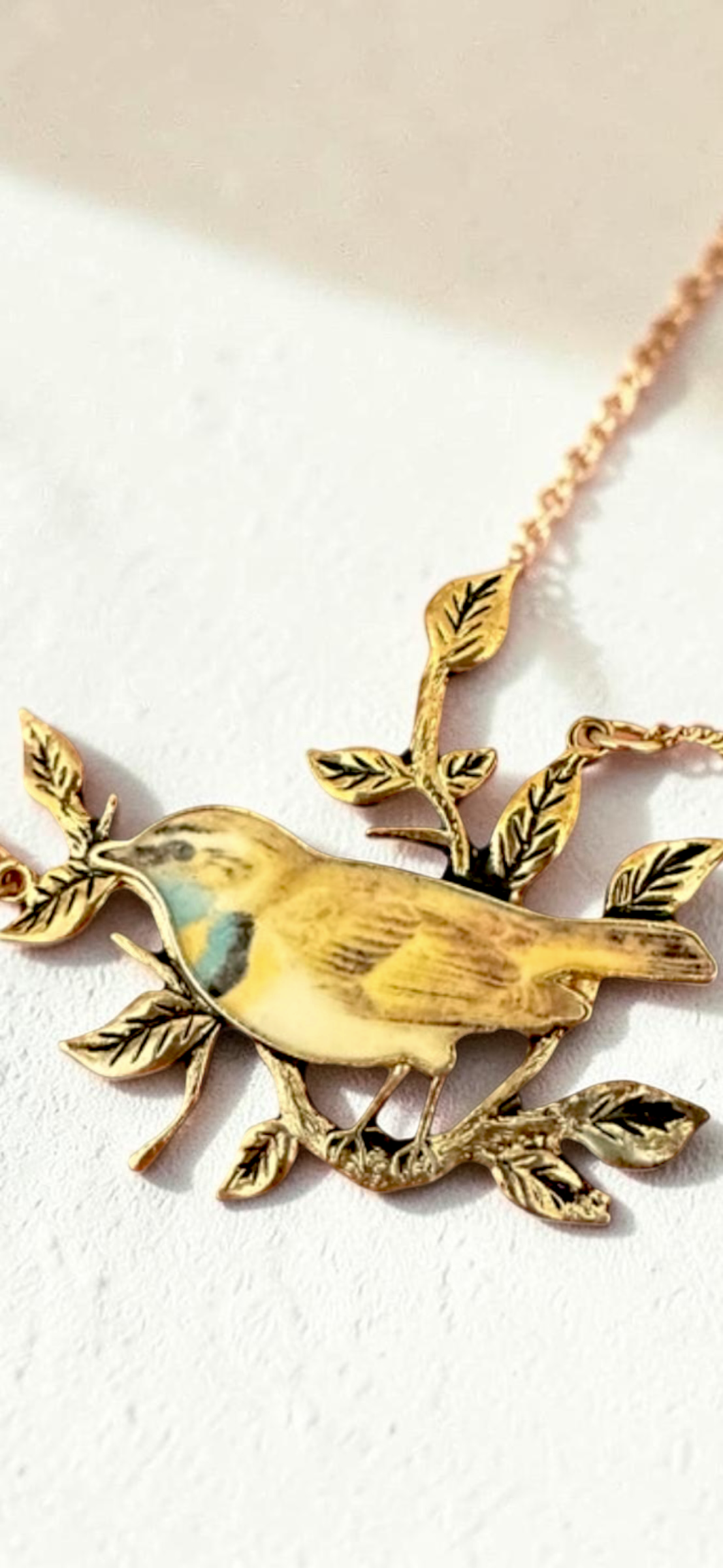 Enamel bird on branch gold tone necklace, close-up of pendant detail