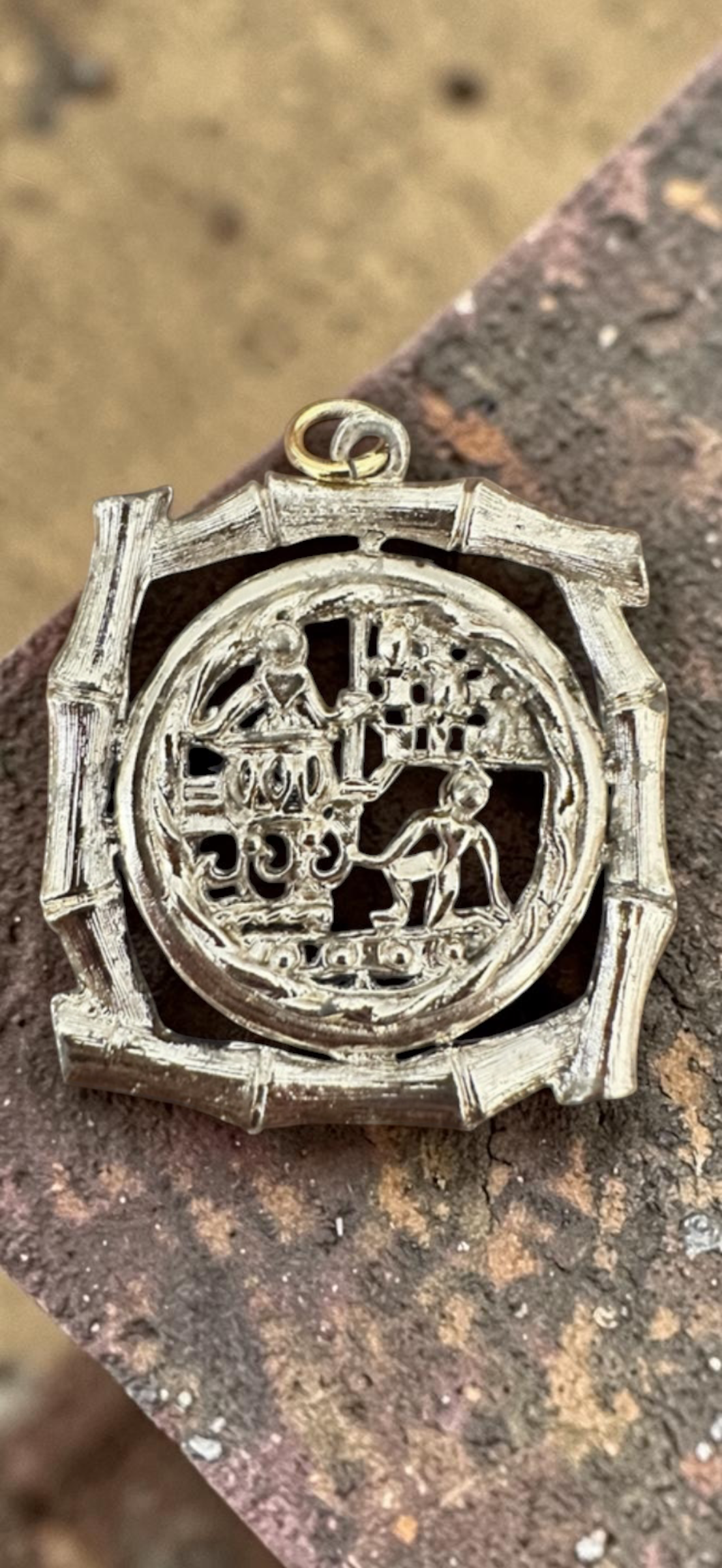 Vintage Chinese scene silver tone bamboo frame pendant, front view on rustic metal