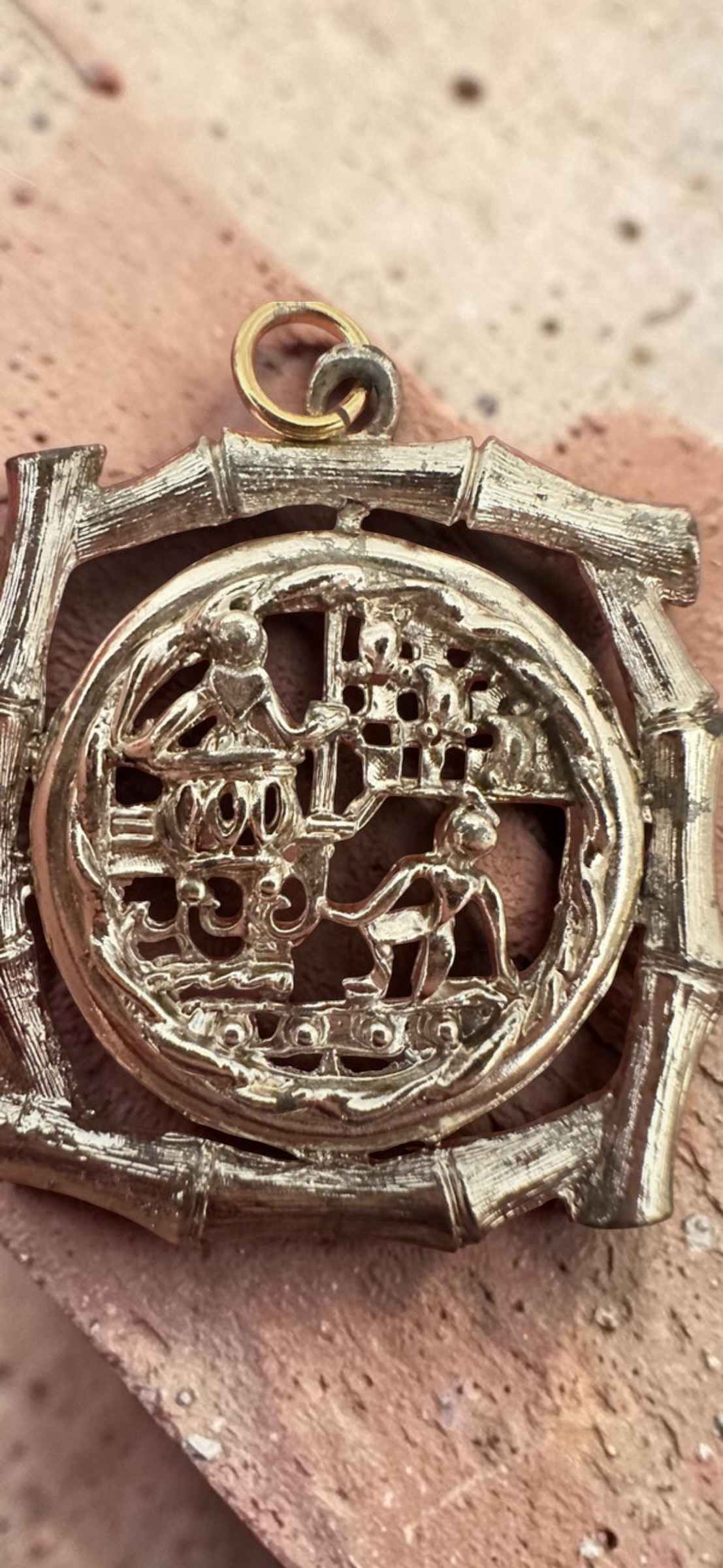 Vintage Chinese scene silver tone bamboo frame pendant, angled view on stone