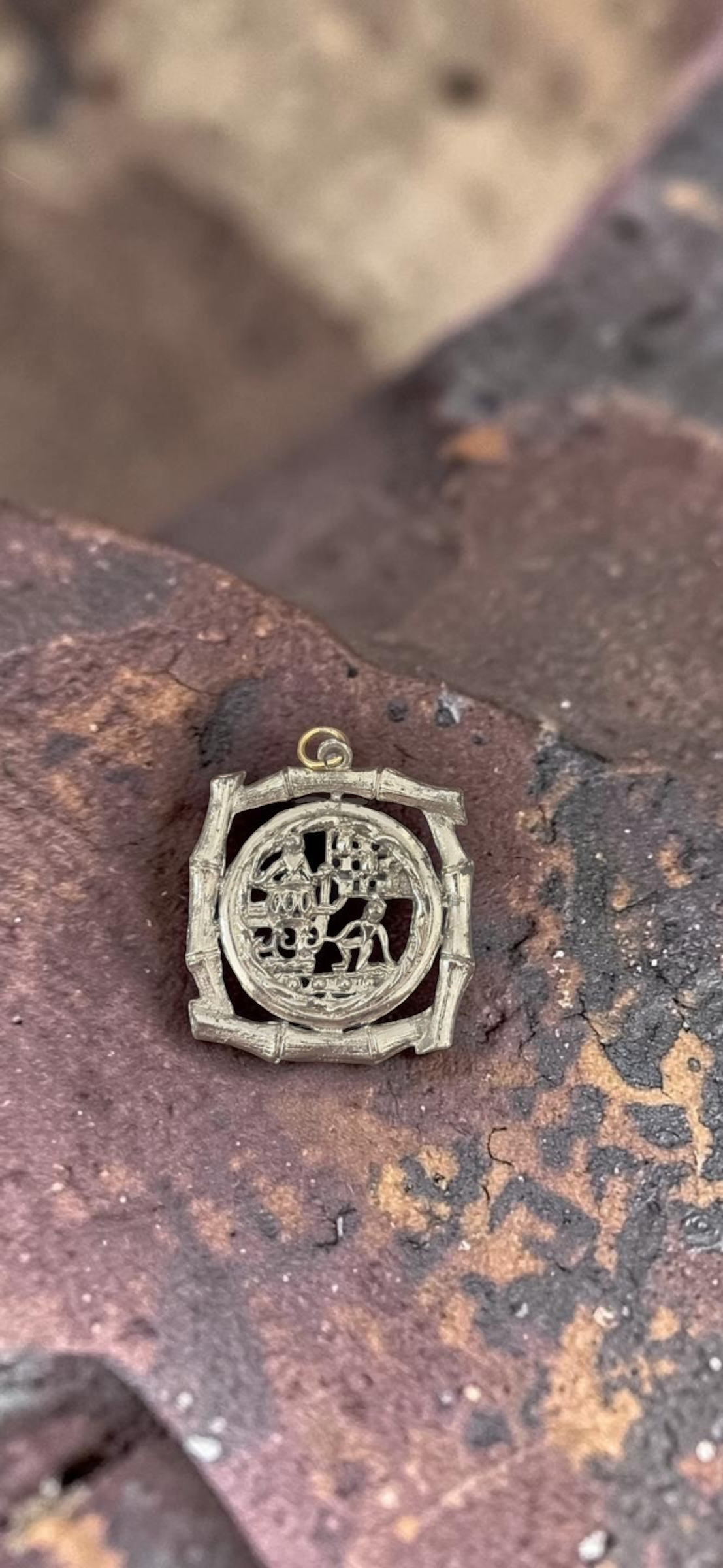 Vintage Chinese scene silver tone bamboo frame pendant, overhead view on rustic metal