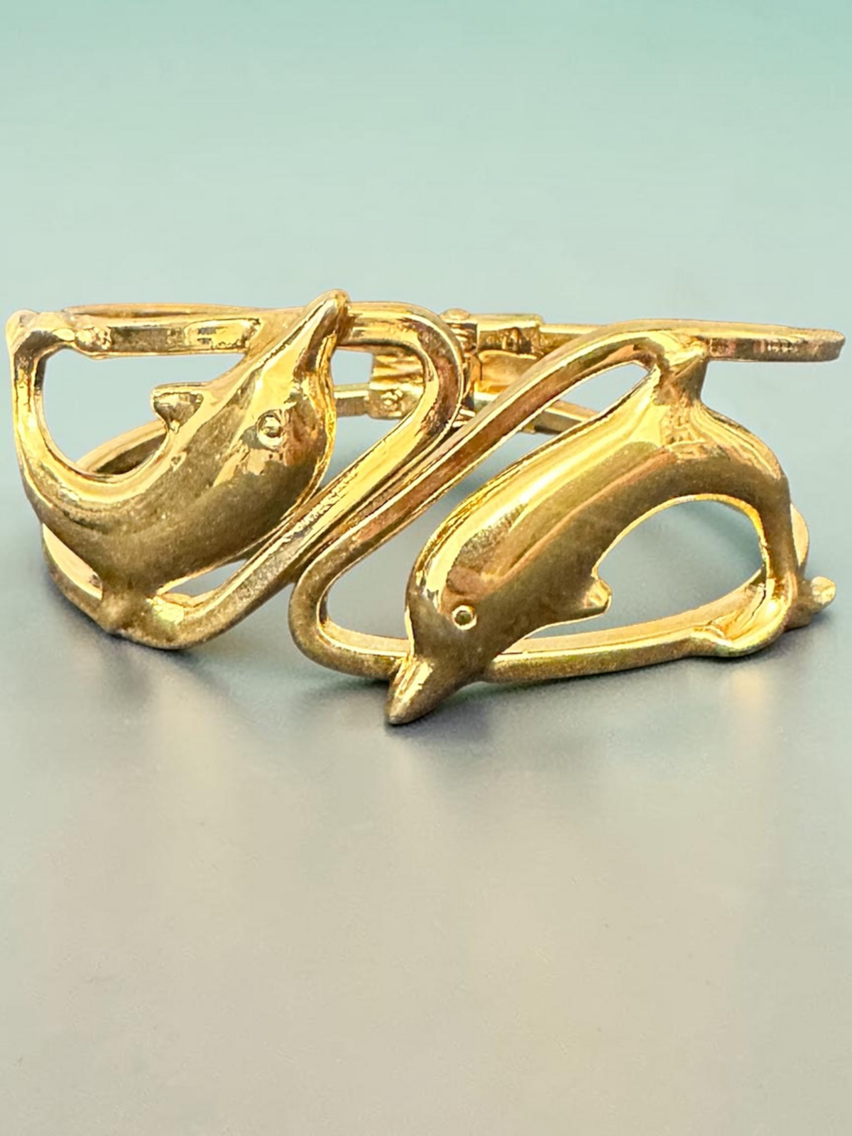 Gold tone dolphin cuff bracelet flat lay