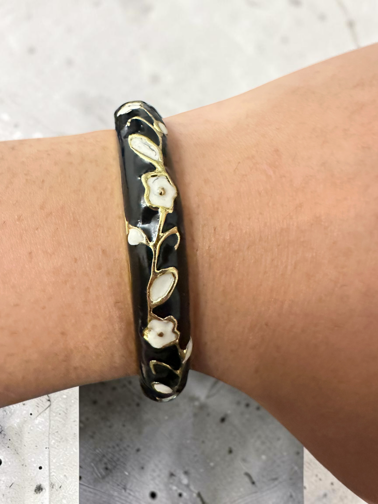 Black enamel floral bangle worn on wrist side view